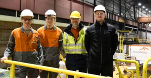 Two engineers in safety gear stand in a steel plant, discussing process automation with FOCUS-1 smart meter valves—part of ArcelorMittal’s innovation efforts to improve efficiency, monitoring, and predictive maintenance in steel production.